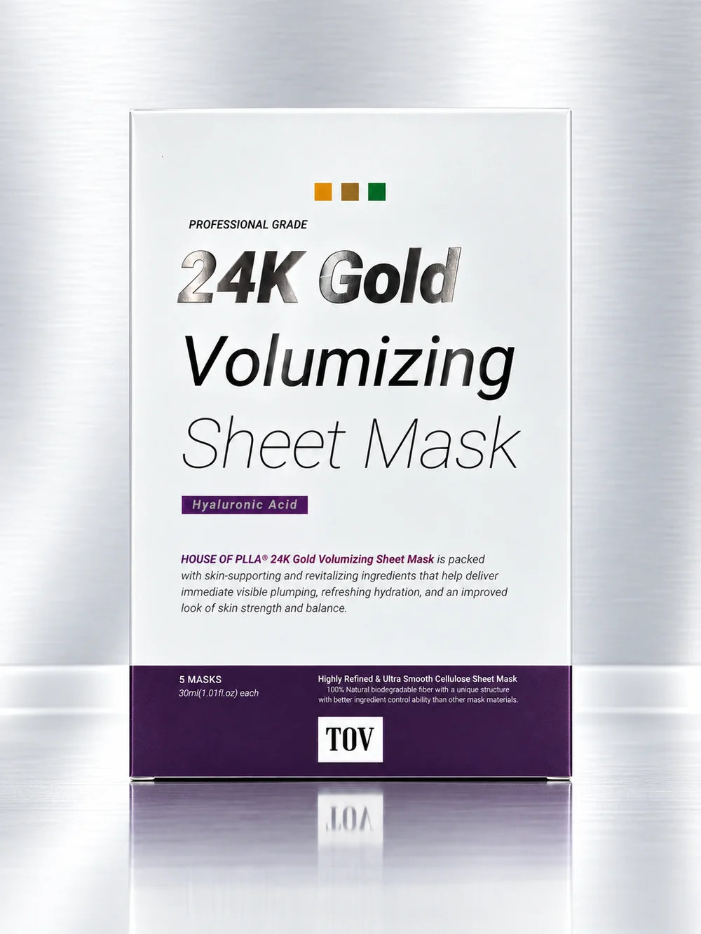 A box of TOV 24K Gold Volumizing Sheet Mask, professional grade, featuring a white and purple design with gold lettering, set against a brushed metal background with a soft reflection.