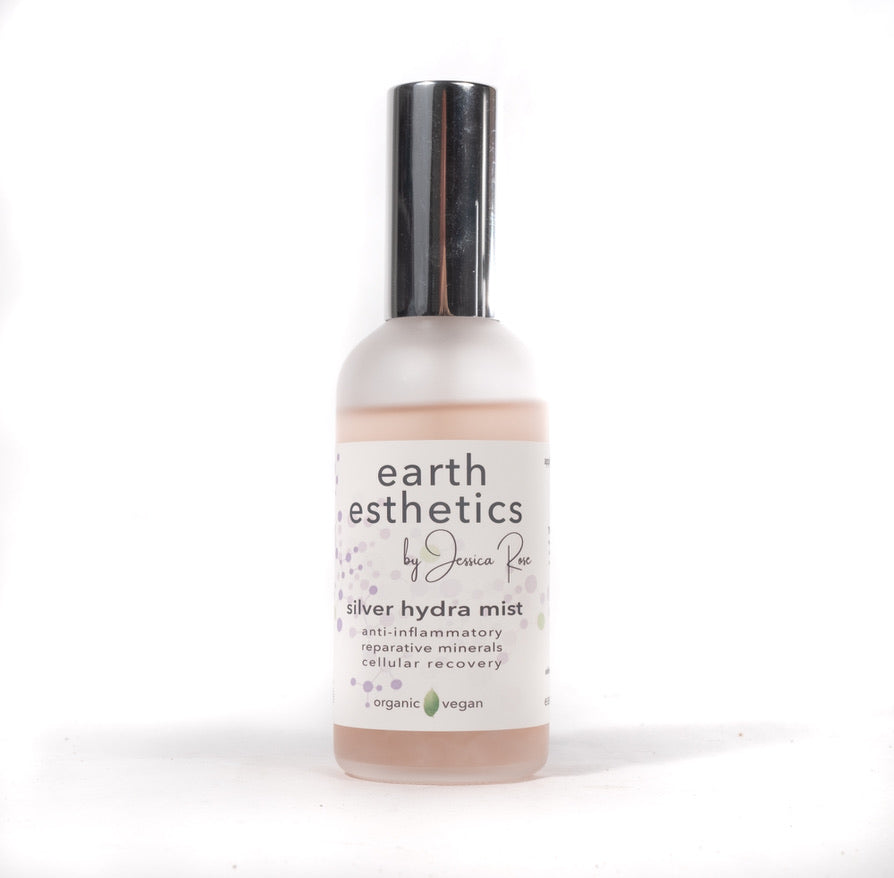 A bottle of Silver Hydra Mist skin toner by Earth Esthetics. The bottle is clear with a white label and a silver pump.